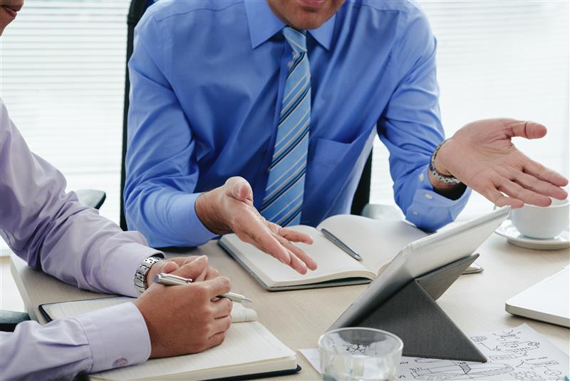 Cropped view of men discussing an annual report using a digital tablet